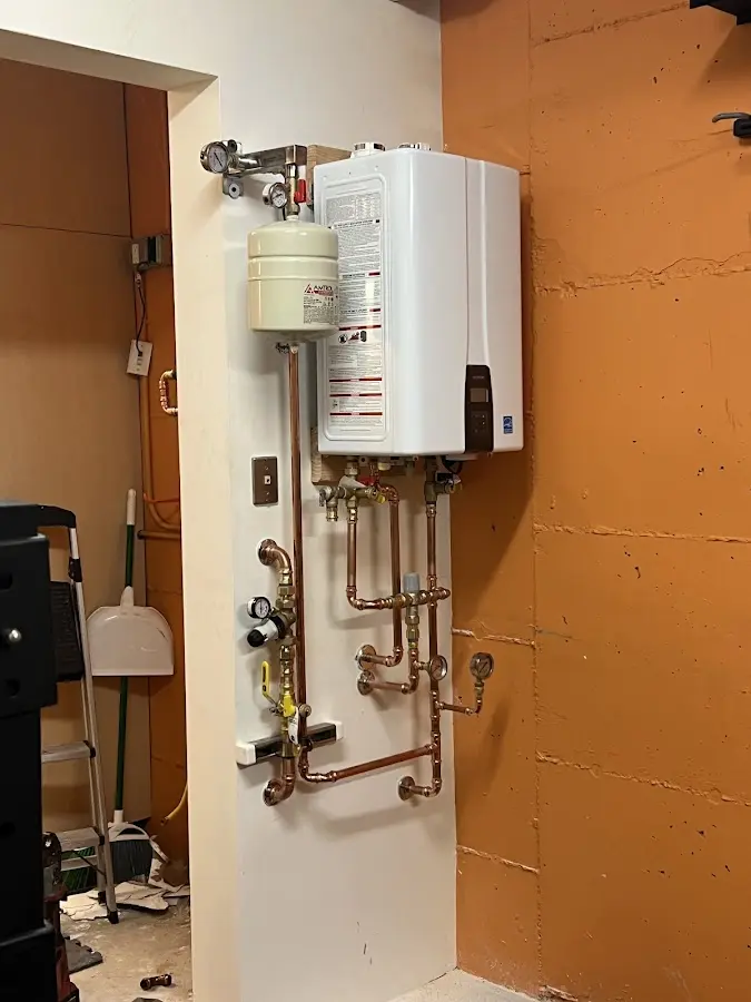Plumbing technician inspecting water heater connections in Larkin